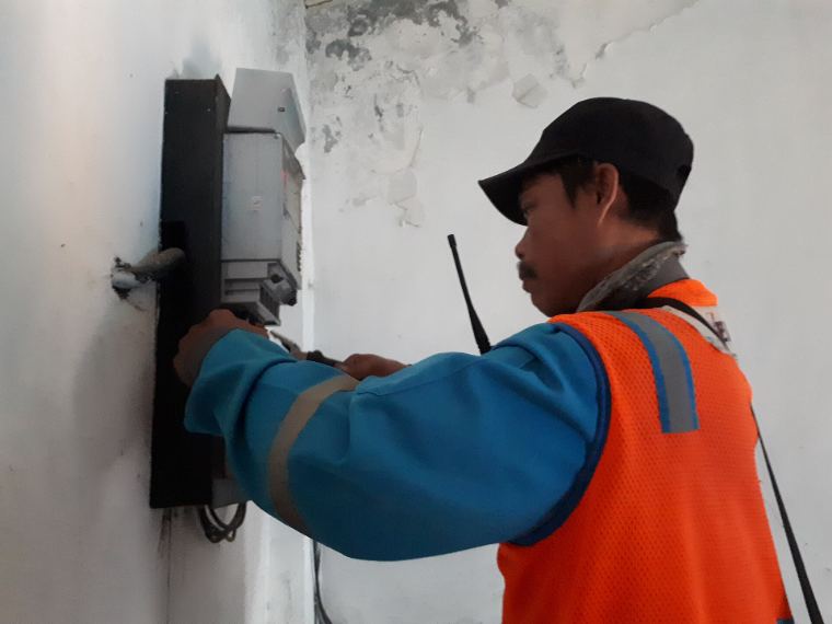 An electrician in a hi-vis vest working on an electricity meter