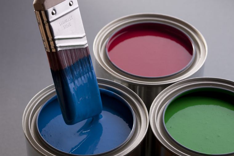 Open paint cans in blue, red and green with a dripping brush